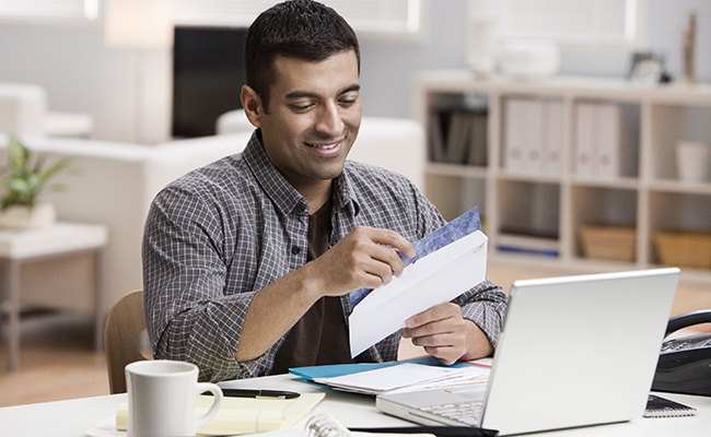 man with papers at a laptop